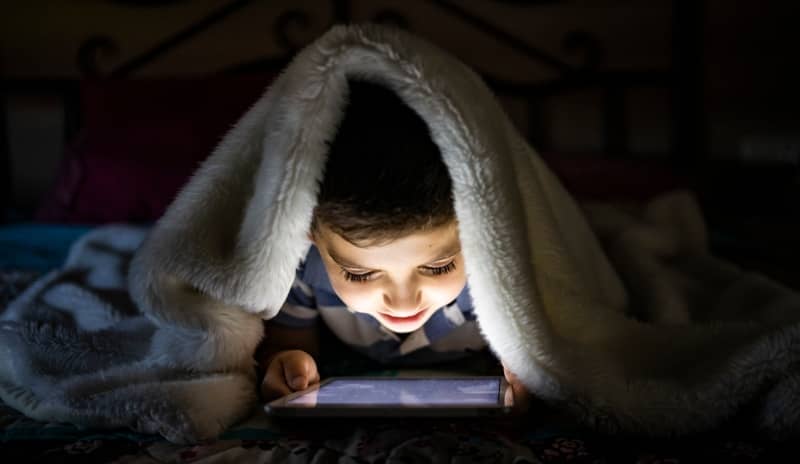 Niño jugando a escondidas porque tiene una adicción a los videojuegos