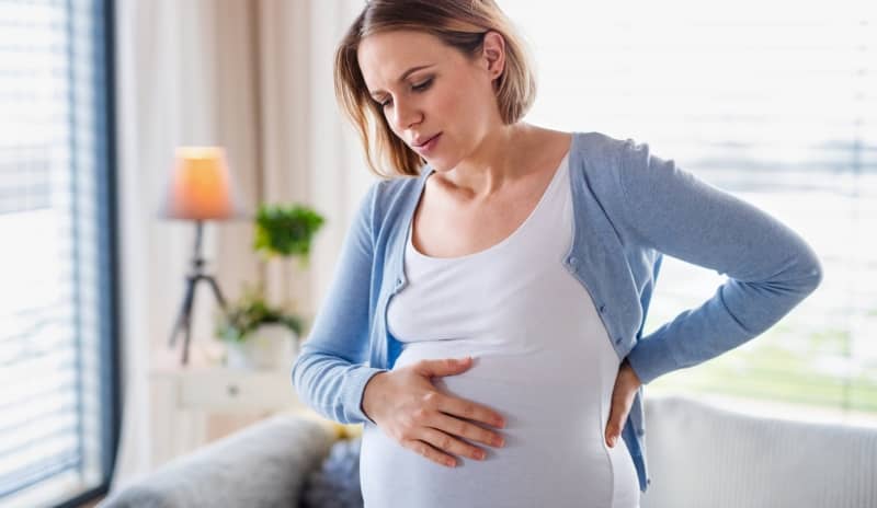 mujer con cólicos en el embarazo tocándose la tripa