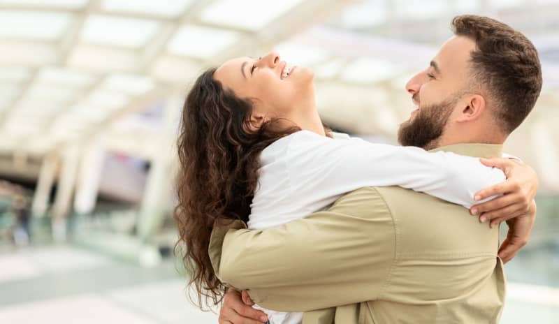 Pareja abrazándose con expresión de alegría en un lugar público, en representación de los beneficios del modelo de relación living apart together.