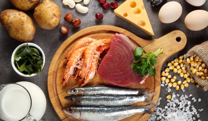 Mesa con variedad de alimentos que destacan por ser alimentos con yodo, como el salmón, bacalao o mariscos.