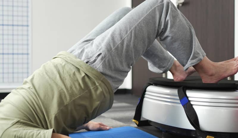 Persona tumbada sobre una colchoneta y las piernas elevadas sobre una plataforma realizando ejercicios para fortalecer el suelo pélvico