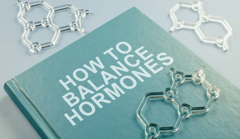 Libro con el título ‘How to Balance Hormones’ junto a figuras de estructuras químicas, representando la búsqueda de soluciones naturales para un desequilibrio hormonal