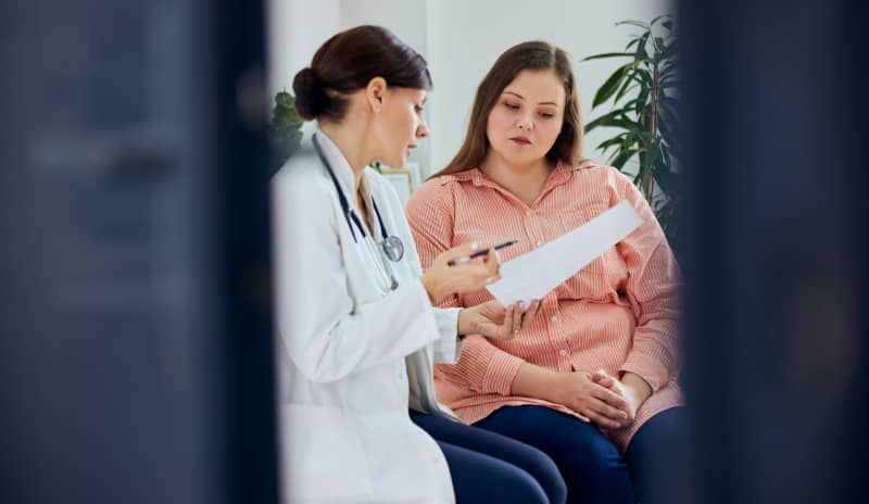 Profesional sanitaria mostrando resultados a una paciente durante una consulta en un ambiente de confianza, en representación de una situación en la que la paciente estaría pasando por la perimenopausia