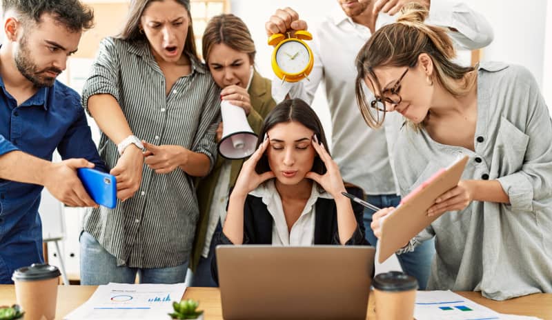 Profesional agobiada por las exigencias de sus compañeros, una situación común en el síndrome del impostor tipo superhéroe