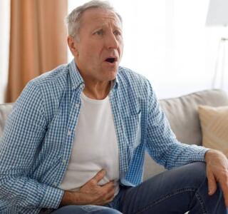 Señor teniendo dolor abdominal, síntomas de un colon irritable