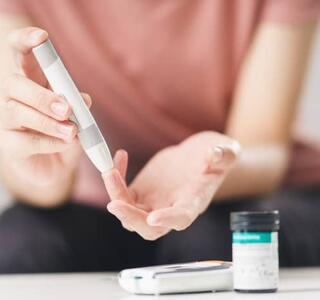 Mujer usando lanceta en el dedo para comprobar el nivel de azúcar en la sangre por medidor de glucosa, salud y médico, diabetes, concepto de glucemia