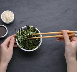 Persona comiendo con palillos alimentos ricos en yodo