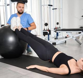Fisioterapeuta supervisando ejercicio de rehabilitación abdominal con fitball para tratar la diástasis abdominal