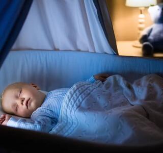 Bebé durmiendo plácidamente en su cuna con luz tenue nocturna, el objetivo que persiguen las familias durante una regresión del sueño