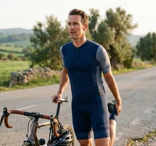 Ciclista haciendo estiramiento de cuádriceps junto a su bicicleta en carretera, uno de los estiramientos para ciclistas recomendados tras la ruta.