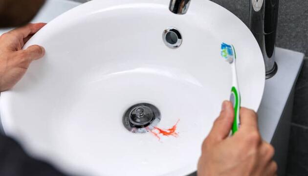 Hombre con sangrado de la encía mientras se cepilla los dientes