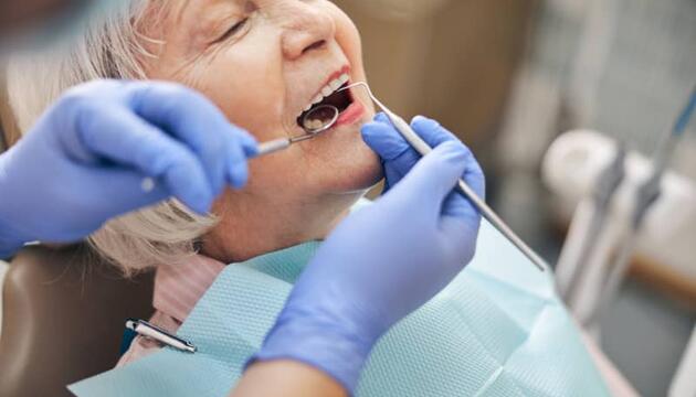 Señora arreglándose la boca con un seguro dental que cubre implantes