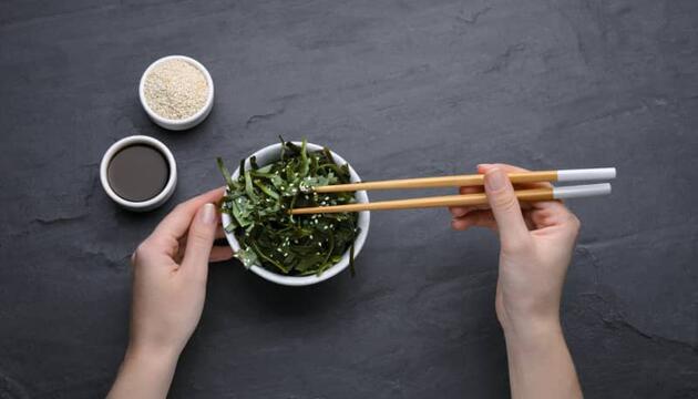 Persona comiendo con palillos alimentos ricos en yodo