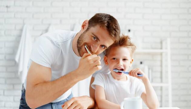 Padre lavándose los dientes con su hijo
