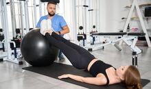 Fisioterapeuta supervisando ejercicio de rehabilitación abdominal con fitball para tratar la diástasis abdominal