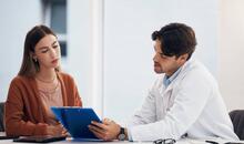 Mujer joven en consulta médica revisando resultados con un profesional sanitario, en el contexto del diagnóstico de menopausia precoz.