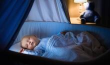 Bebé durmiendo plácidamente en su cuna con luz tenue nocturna, el objetivo que persiguen las familias durante una regresión del sueño